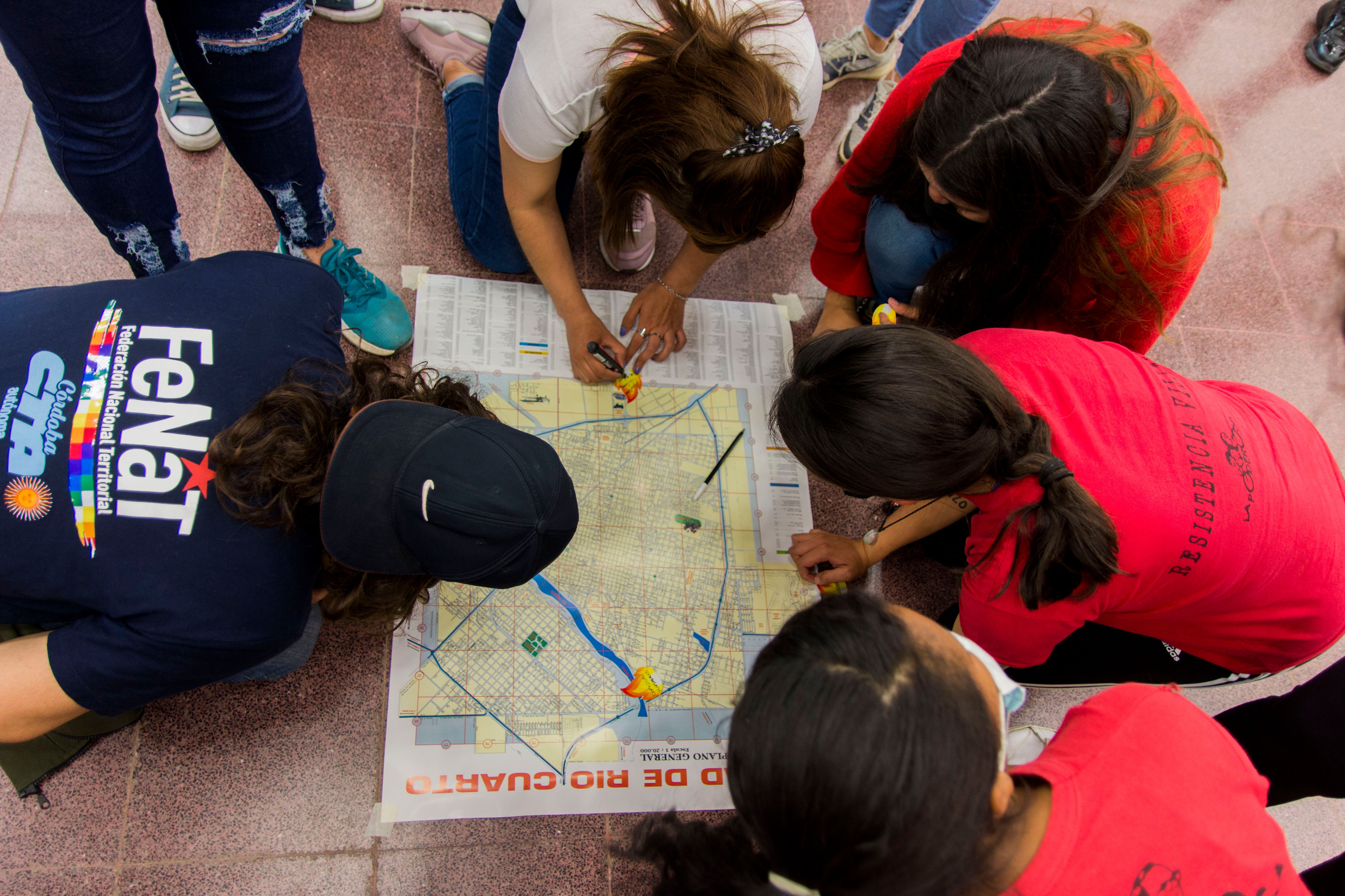 photograph taken from a high position of a group of women working on a map that is placed on the ground