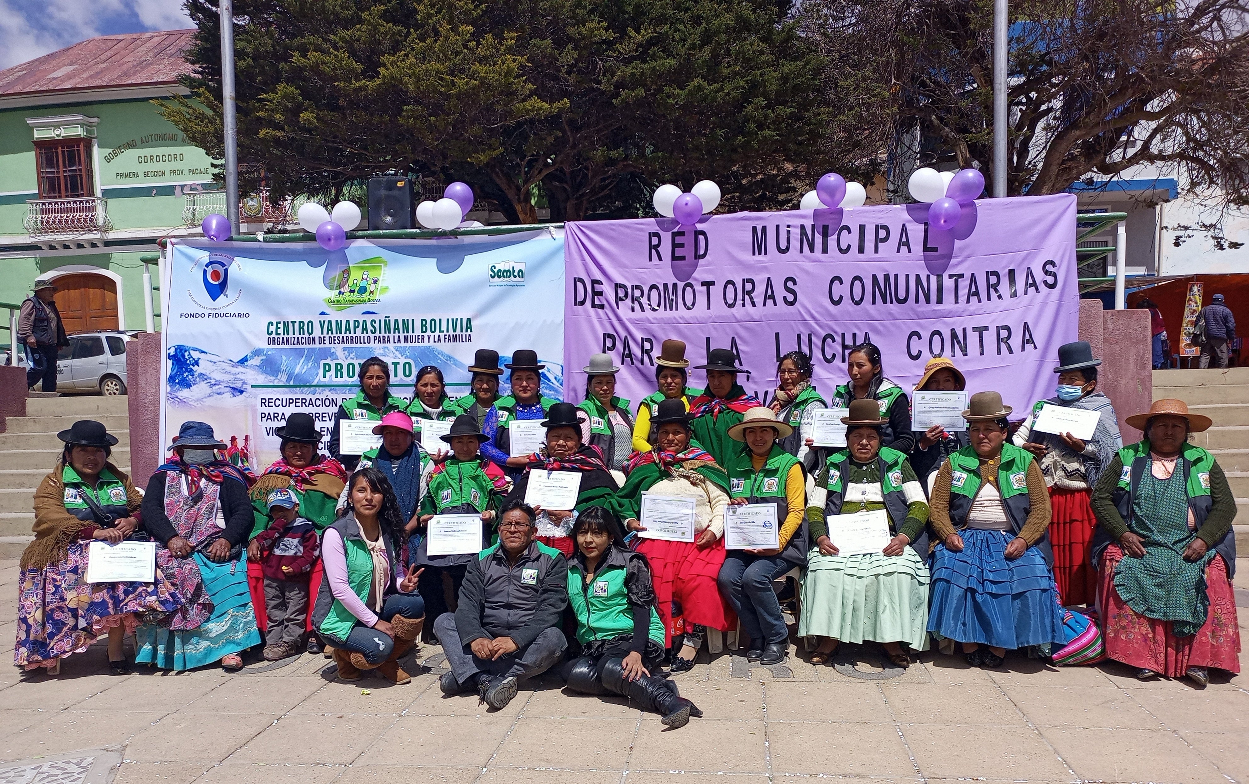 Group of women outside, sitting in front of large banners