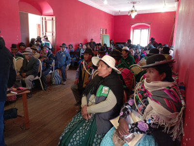 Group of people sitting in a room with red walls listening to someone speak