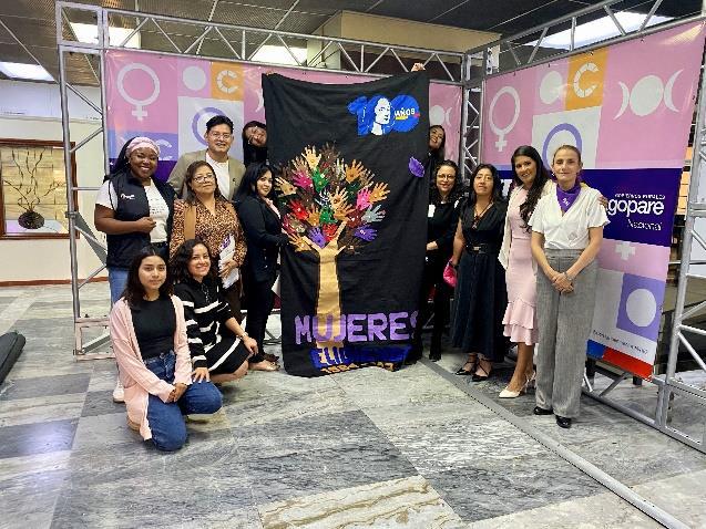 Group of women standing next to a tissue banner inside a room