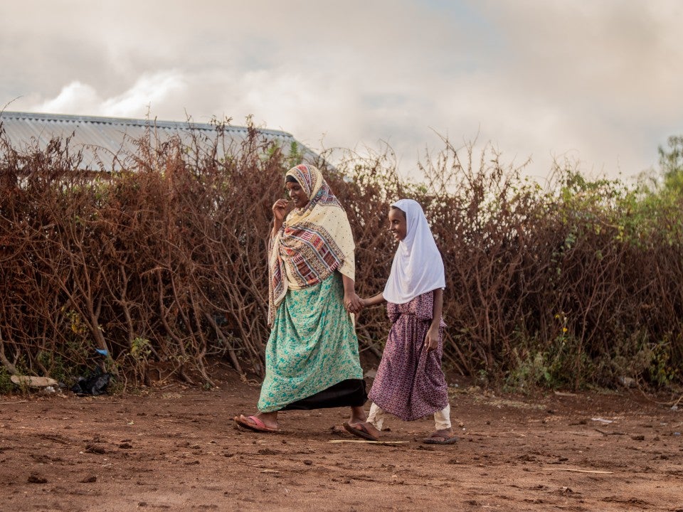 A woman and girl participating in a project from ISF walk together. Muhammed Isra, photographer: Nyasha Kadandara, place: Magalo cad