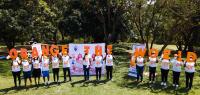 Group of people standing in a yard holding up big orange letters that read Orange the World