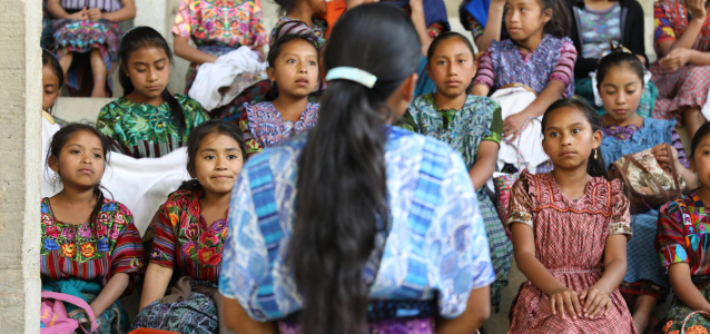 Woman seen from the back standing in front of a crow of young women in Guatemala